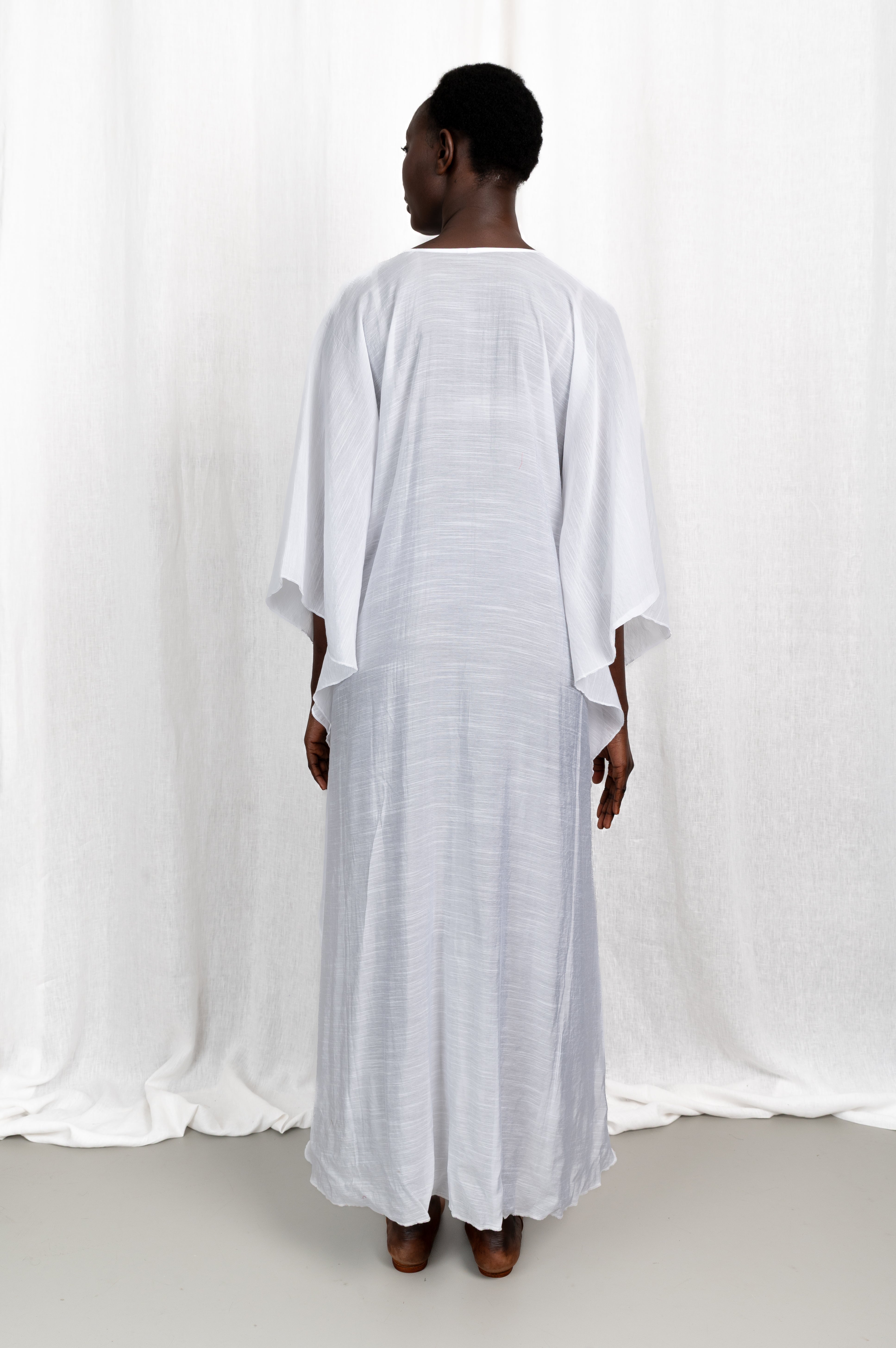 Modèle portant la robe Maali en voile de coton blanc, vue de dos
