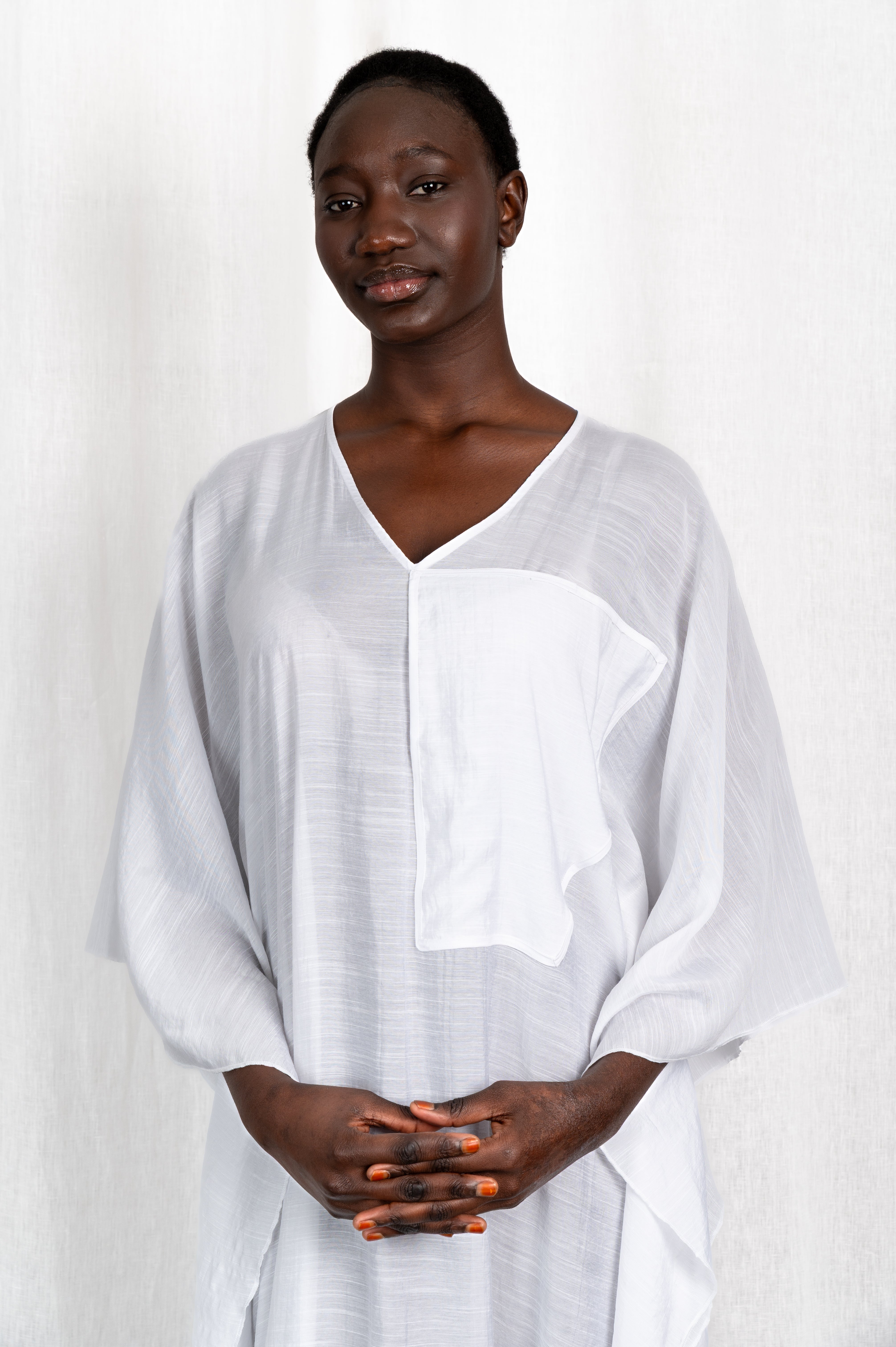 Modèle portant la robe Maali en voile de coton blanc, vue de portrait