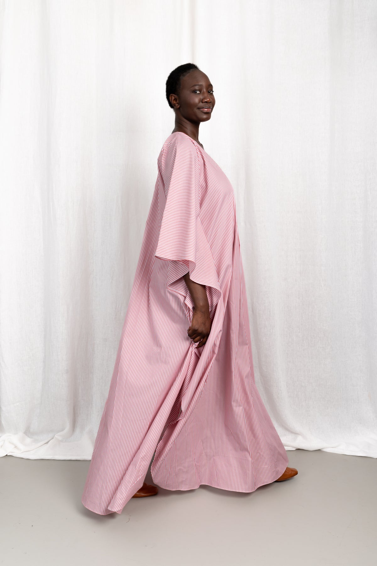 Modèle portant la robe Nia rose en coton et rayures roses, vue en mouvement #couleur_rose