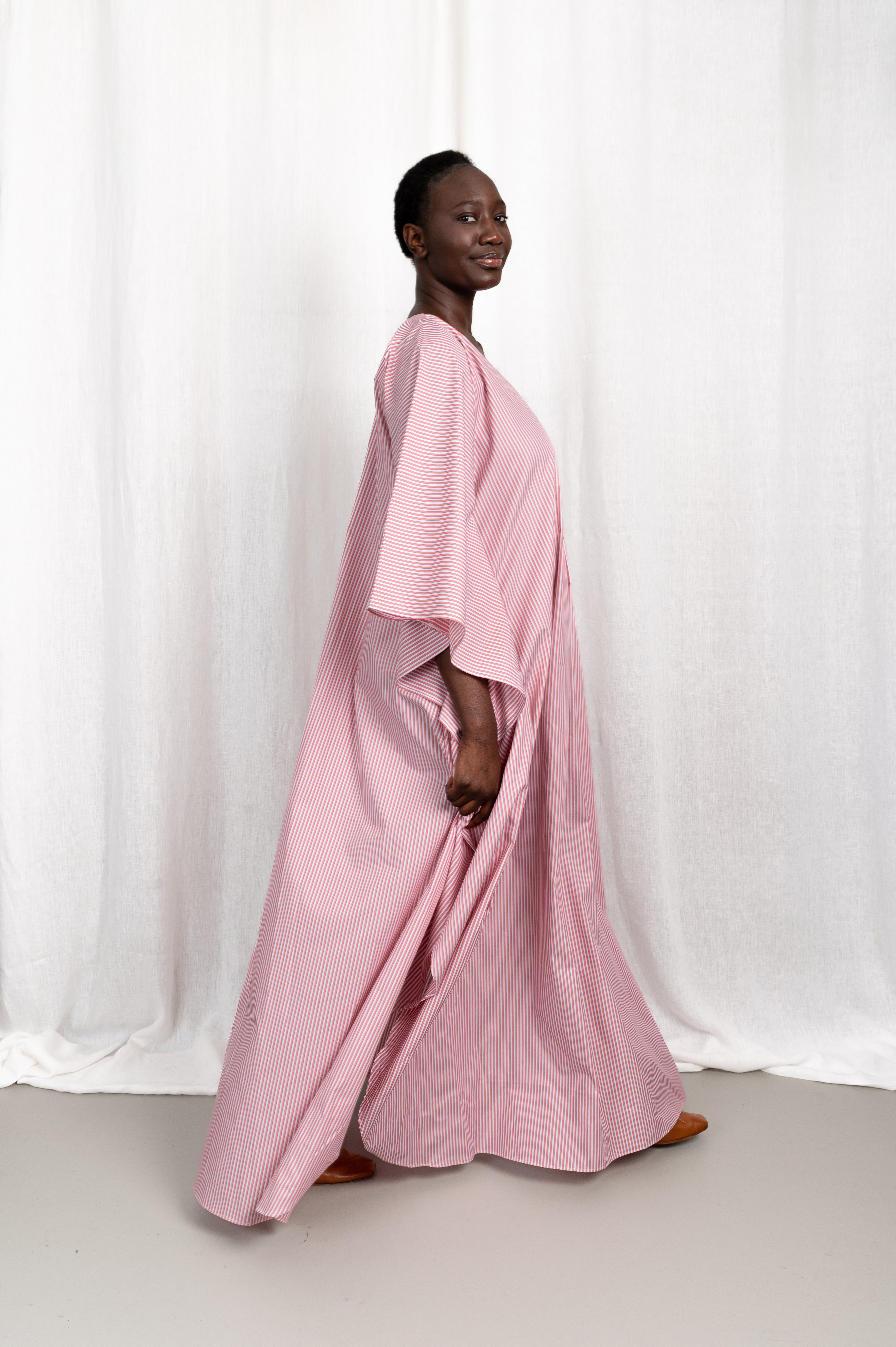 Modèle portant la robe Nia rose en coton et rayures roses, vue en mouvement #couleur_rose