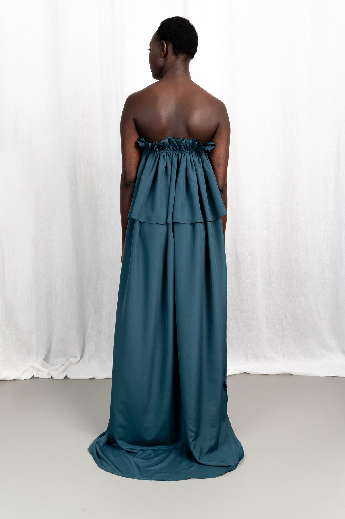 Modèle portant la robe Tamït en crêpe de Chine satiné, vue de dos #couleur_bleu vert profond